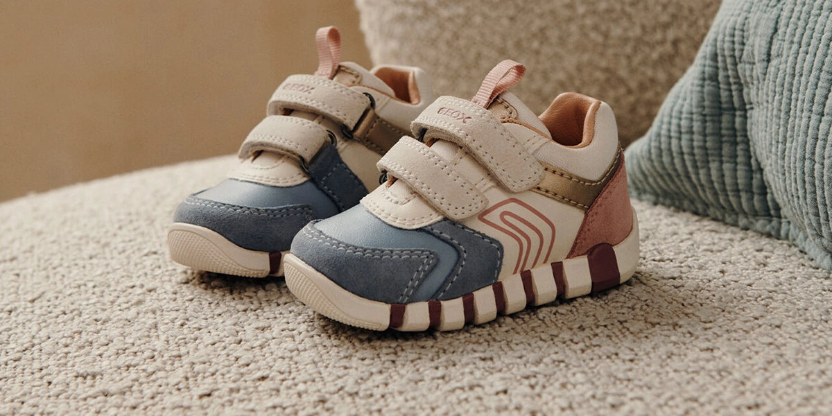 Sneakers colorate da bambina 0-3 anni appoggiate su un divano